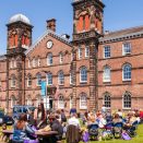 People sitting at tables in front of a brick building.